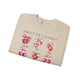 Sweat-shirt beige plié orné d'illustrations de fraises et de cerises avec des nœuds roses.