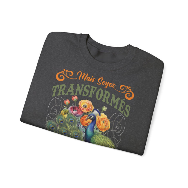 Sweat-shirt gris foncé plié avec une illustration de paon et de fleurs et le texte Mais Soyez Transformés.