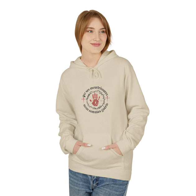 Une femme porte un sweat à capuche beige avec une impression religieuse sur la poitrine.