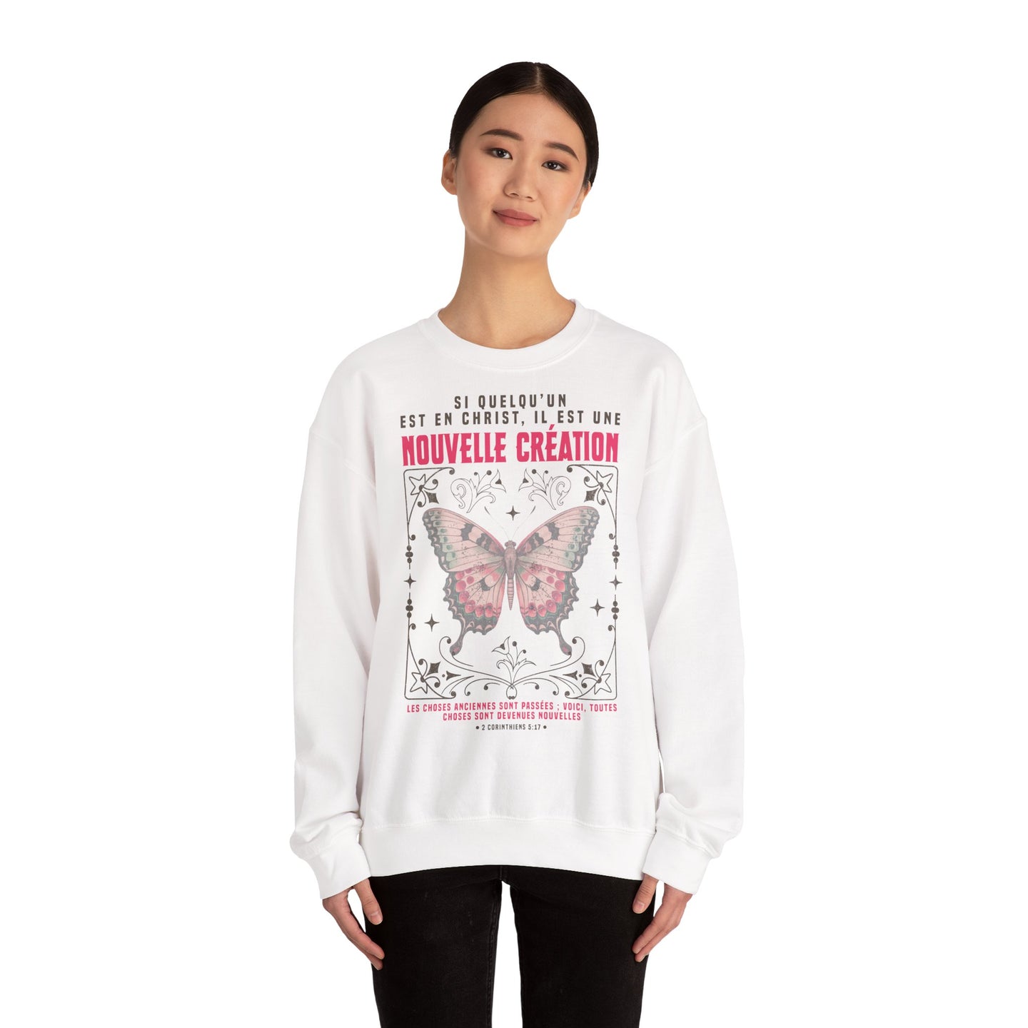 Une femme porte un sweat-shirt blanc avec un papillon et un texte biblique en français.