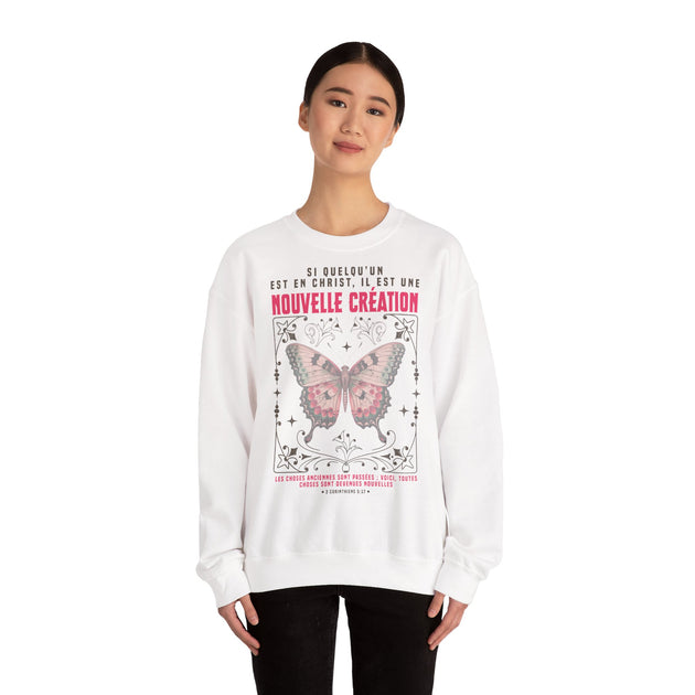 Une femme porte un sweat-shirt blanc avec un papillon et un texte biblique en français.