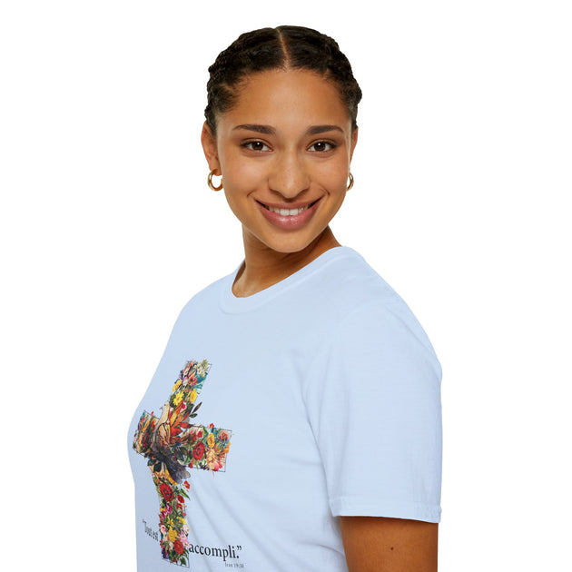 Une femme porte un t-shirt blanc orné d'une croix fleurie et de l'inscription Tout est accompli.