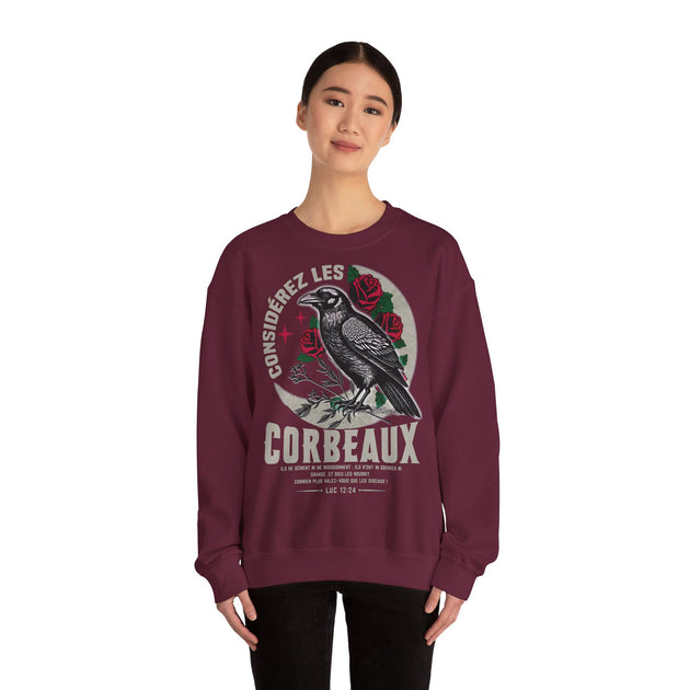 Une femme porte un sweatshirt bordeaux orné d'une illustration de corbeau et de roses.