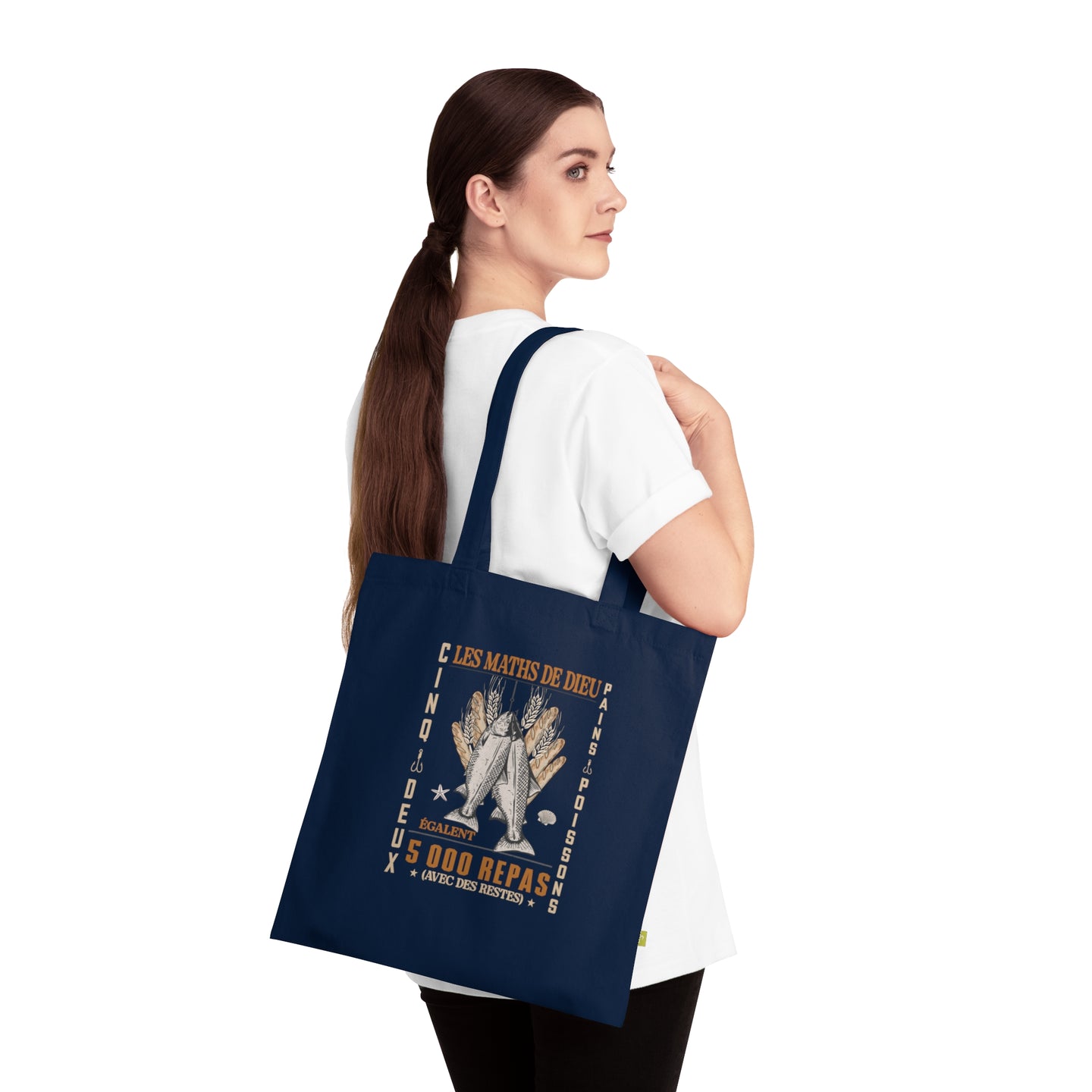 Une femme porte un tote bag bleu marine en coton biologique orné d'une illustration religieuse.