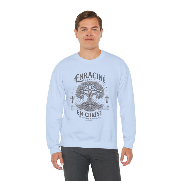 Un homme porte un sweatshirt bleu clair avec un motif d'arbre et le texte Enraciné en Christ.