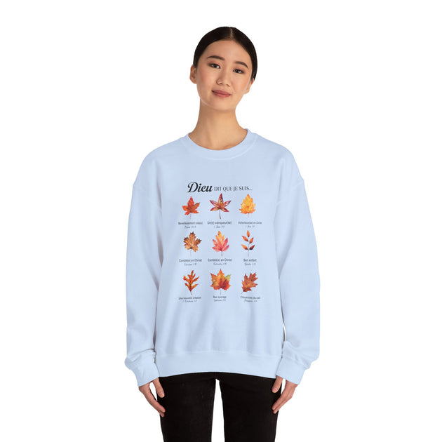 Une femme porte un sweatshirt blanc orné de feuilles colorées et de textes bibliques en français.
