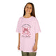 Une jeune fille porte un t-shirt rose orné d'un nœud vichy et d'une croix avec un texte religieux.