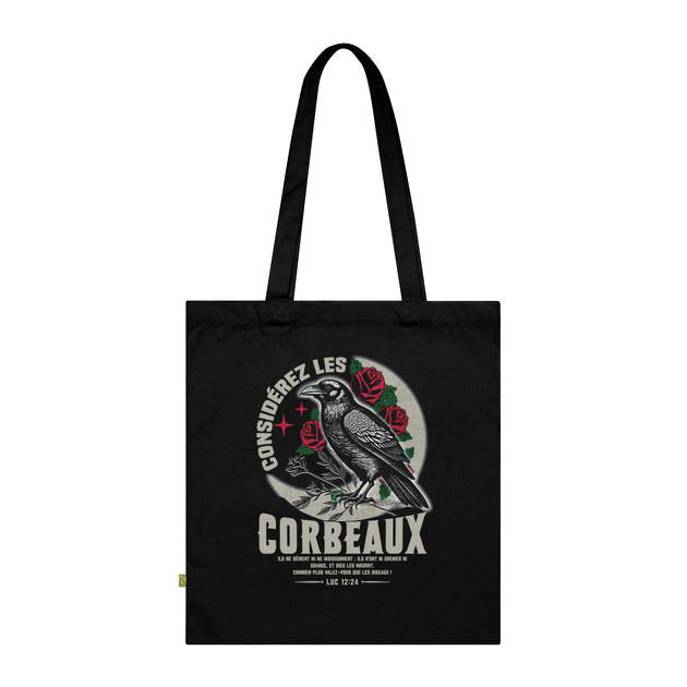 Tote bag noir en coton biologique illustré d'un corbeau entouré de roses avec un verset biblique.
