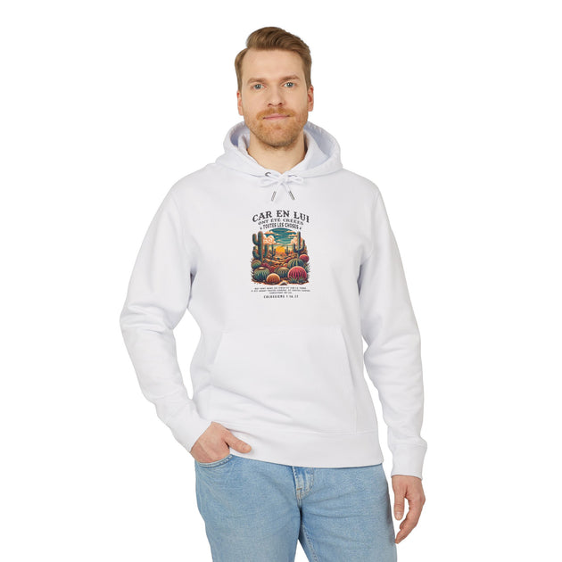 Un homme porte un sweat à capuche blanc en coton avec une illustration de désert et un verset.