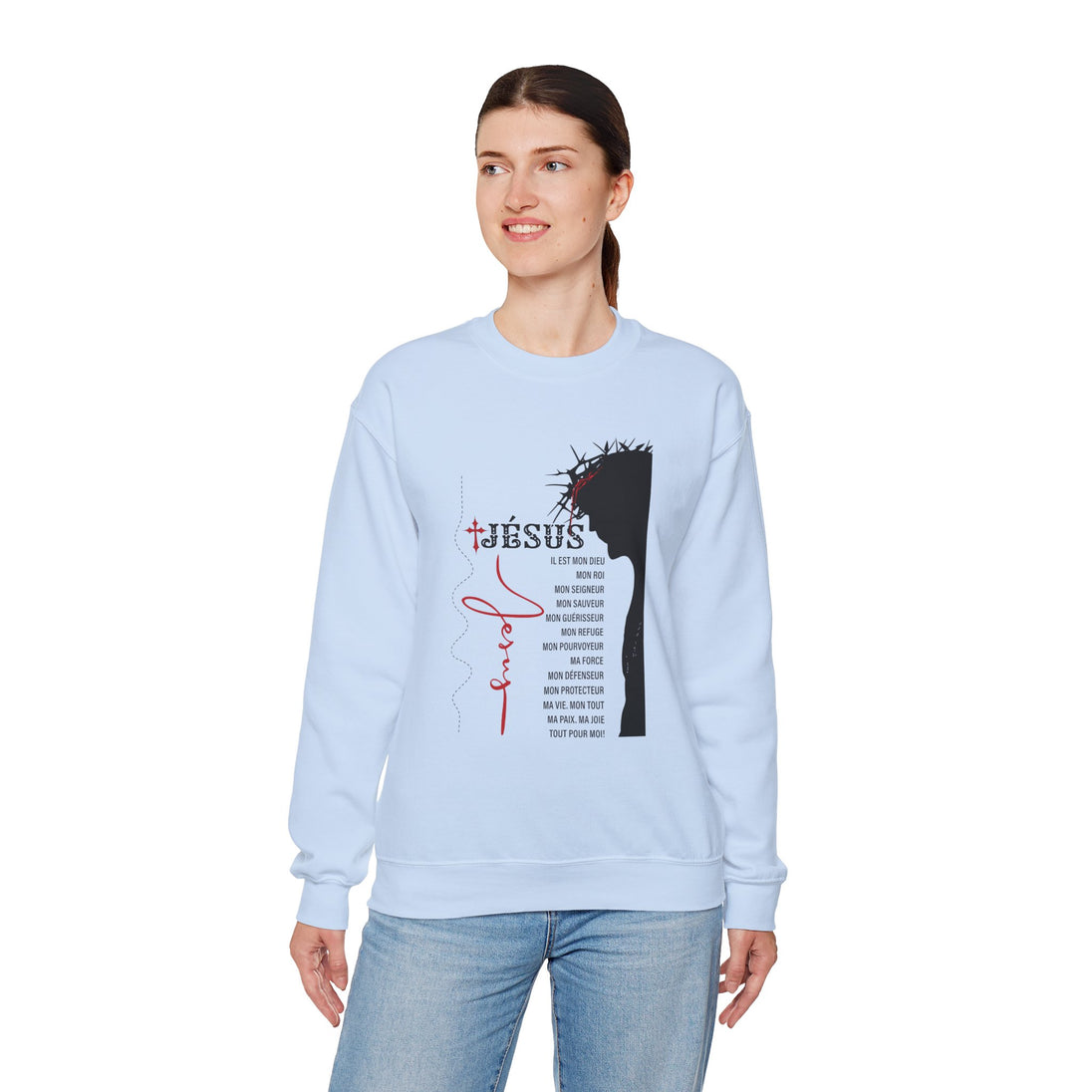 Une femme porte un sweat-shirt bleu clair orné d'une illustration religieuse et de texte en français.