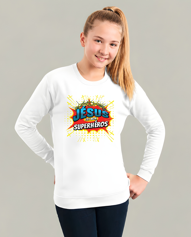 Sweat blanc enfant avec logo BD coloré Jésus est mon Superhéros, porté par une jeune fille.