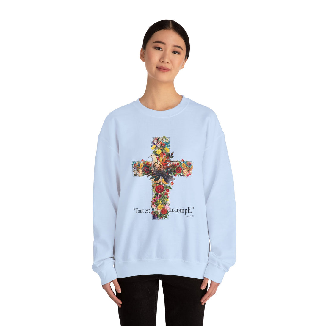 Une femme porte un sweat-shirt blanc orné d'une croix florale et de l'inscription Tout est accompli.
