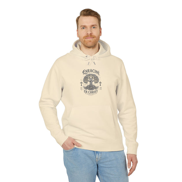 Un homme porte un sweat à capuche beige avec un motif d'arbre et l'inscription Enraciné en Christ.