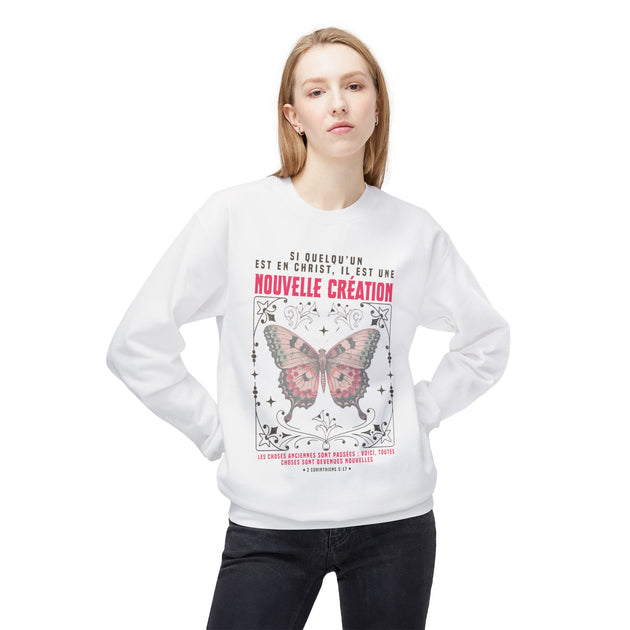 Une femme porte un sweat-shirt blanc avec un motif de papillon et un texte religieux en français.
