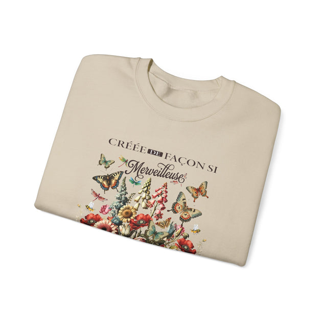 Sweat-shirt beige plié orné d'un motif floral et de papillons avec l'inscription Créée de façon merveilleuse.