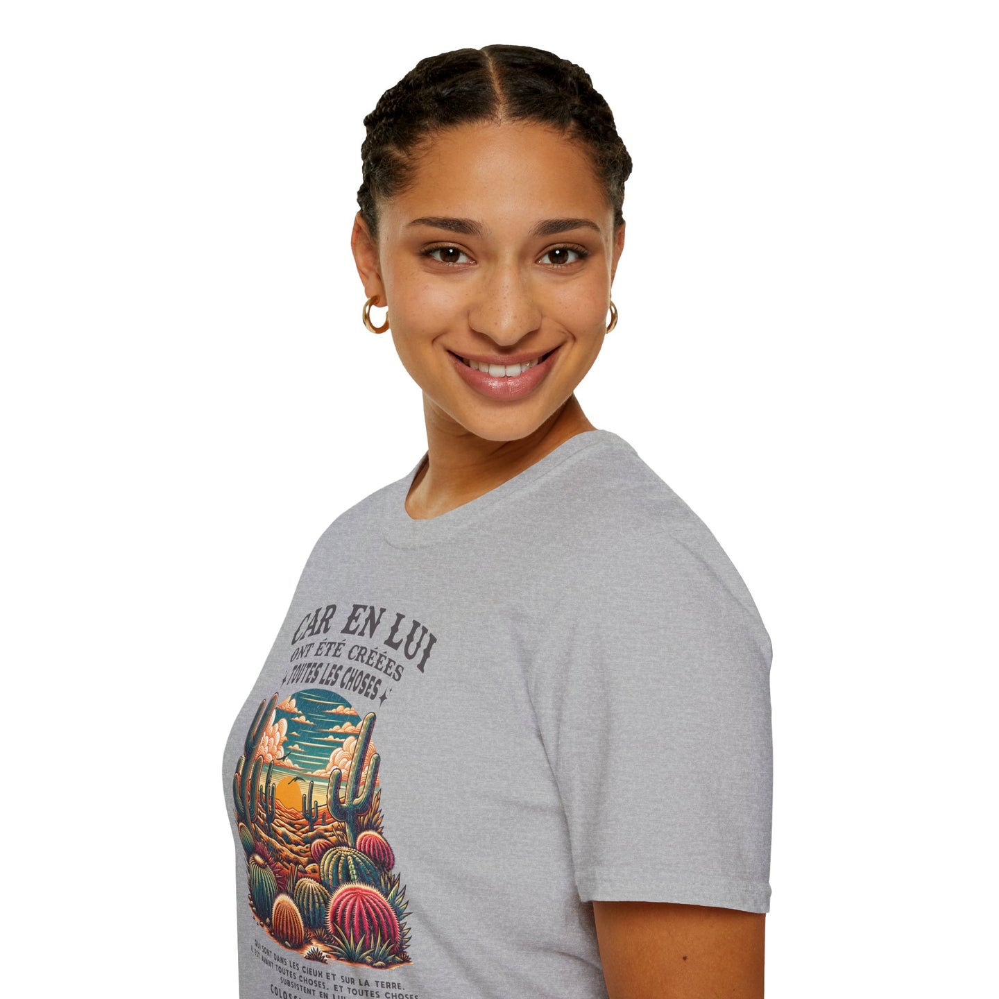 Une femme porte un t-shirt gris orné d'un motif de désert et d'un texte religieux en français.