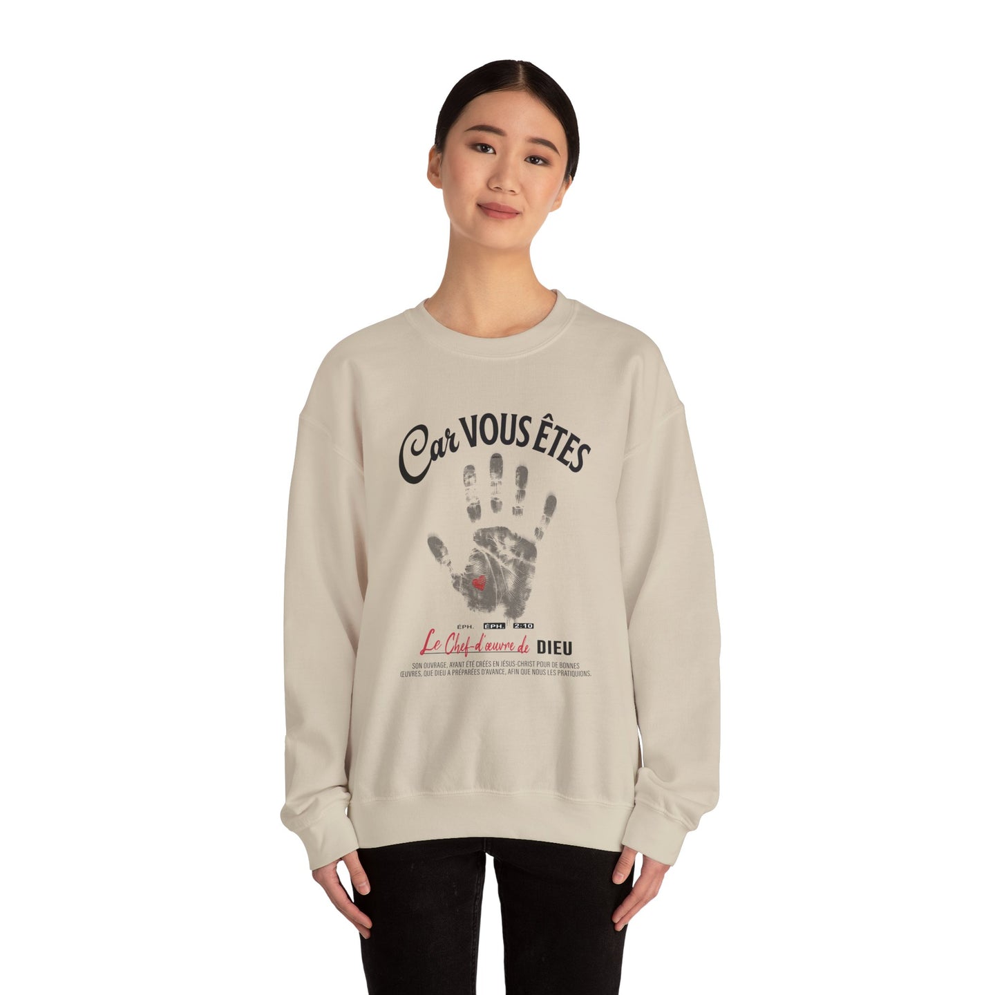 Une femme porte un sweat-shirt beige avec une empreinte de main et un texte religieux en français.