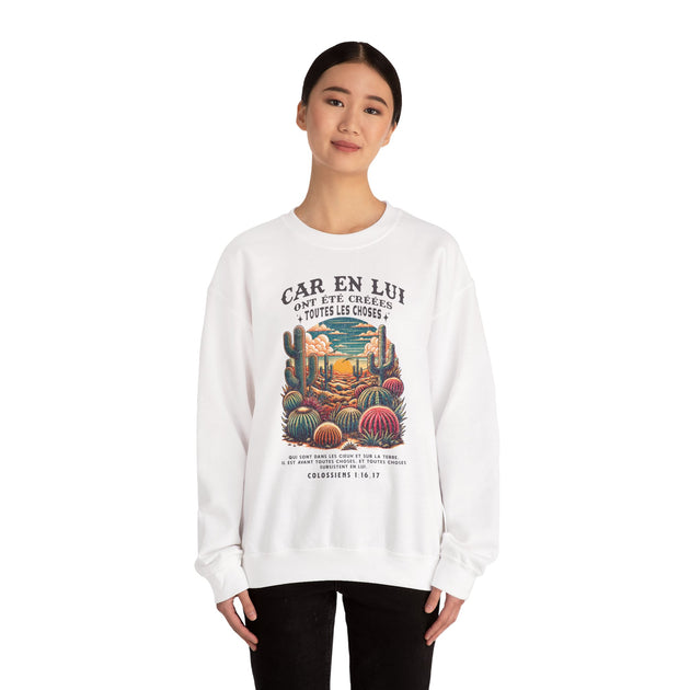 Une femme porte un sweat-shirt blanc avec une illustration de cactus et un texte biblique.