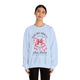 Une femme porte un sweat-shirt bleu clair avec un motif de nœud rose et une croix chrétienne.
