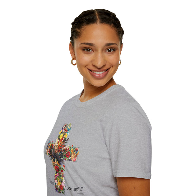 Une femme porte un t-shirt gris orné d'une croix fleurie avec l'inscription Tout est accompli.