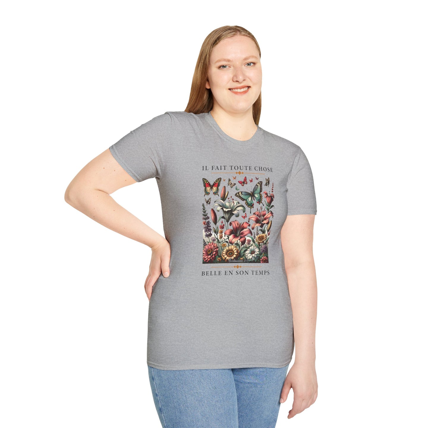 Une femme porte un t-shirt gris orné d'un motif floral et de papillons avec une inscription.