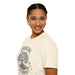 Une femme porte un t-shirt beige en coton avec une illustration d'arbre et le texte Enraciné en Christ.