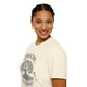 Une femme porte un t-shirt beige en coton avec une illustration d'arbre et le texte Enraciné en Christ.