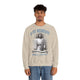 Un homme porte un sweatshirt beige avec une illustration religieuse et le texte Il est ressuscité.