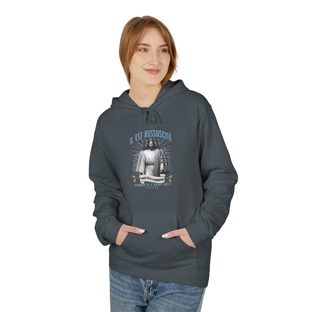 Une femme porte un sweat à capuche gris foncé avec une illustration religieuse sur la poitrine.