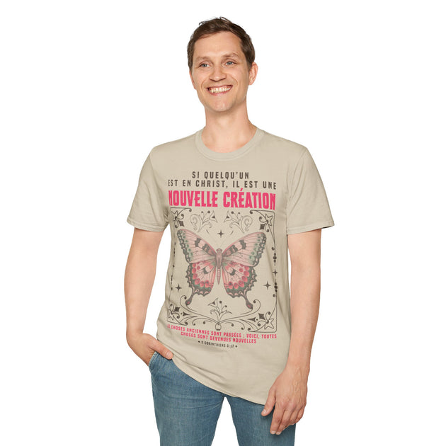 Un homme porte un t-shirt beige avec un papillon et le verset biblique 2 Corinthiens 5:17.