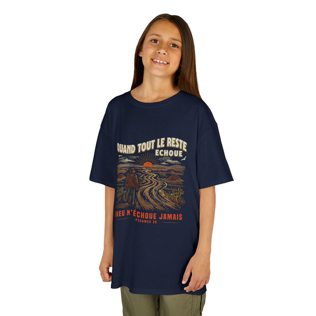 Un enfant porte un t-shirt bleu marine avec une illustration de paysage et un message religieux.