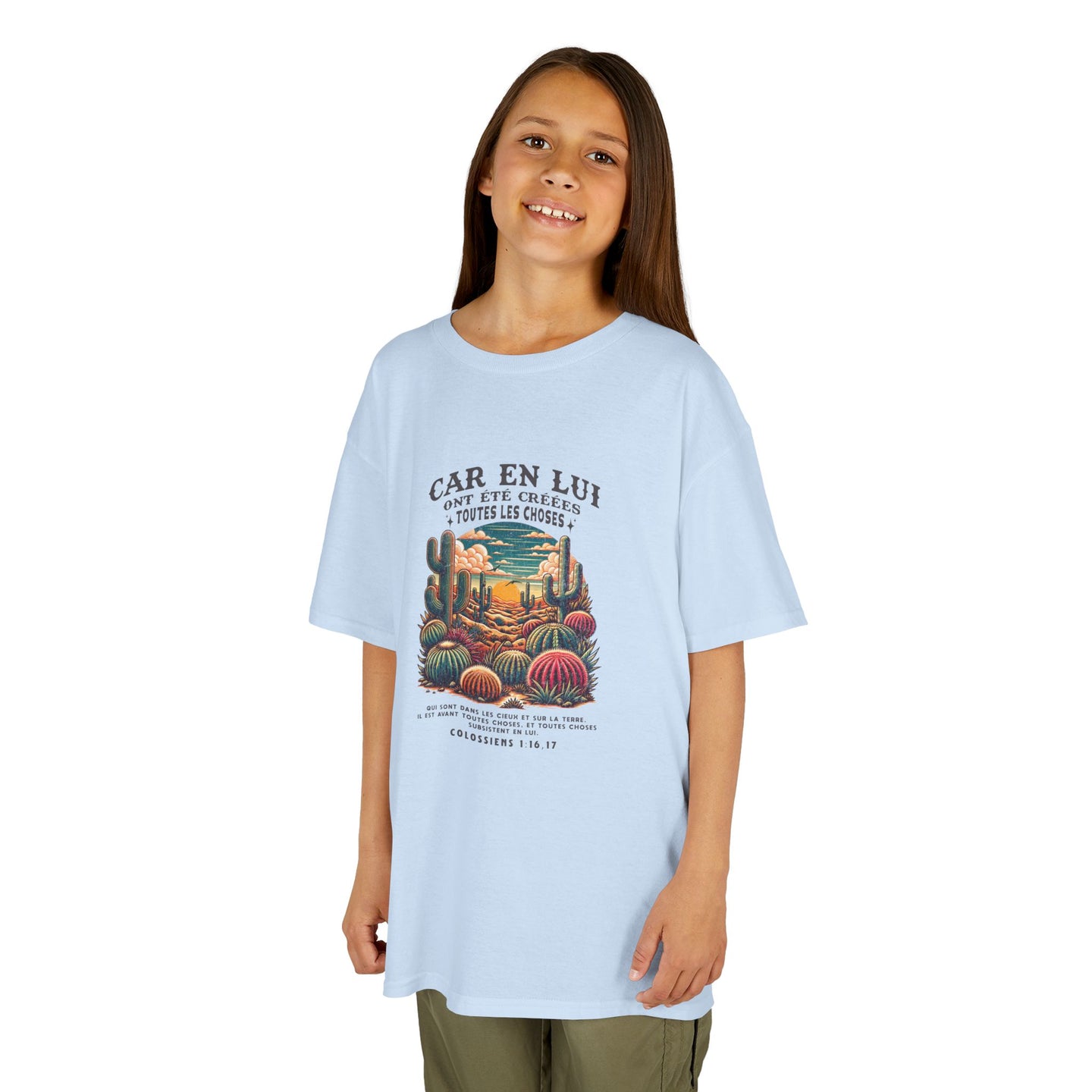 Une enfant porte un t-shirt bleu clair avec une illustration de cactus et un texte biblique.