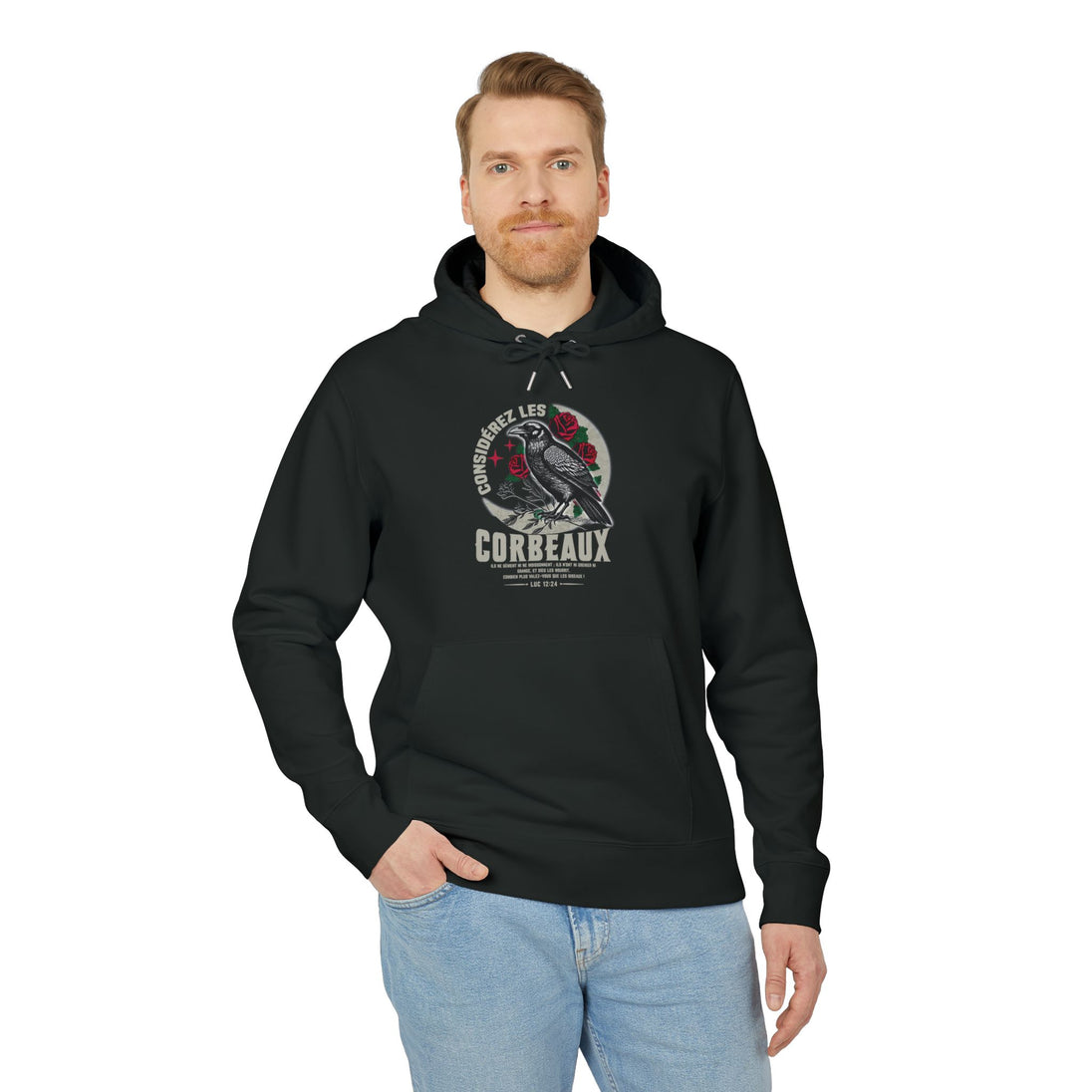 Un homme porte un sweat à capuche noir avec une illustration de corbeau et un texte biblique.