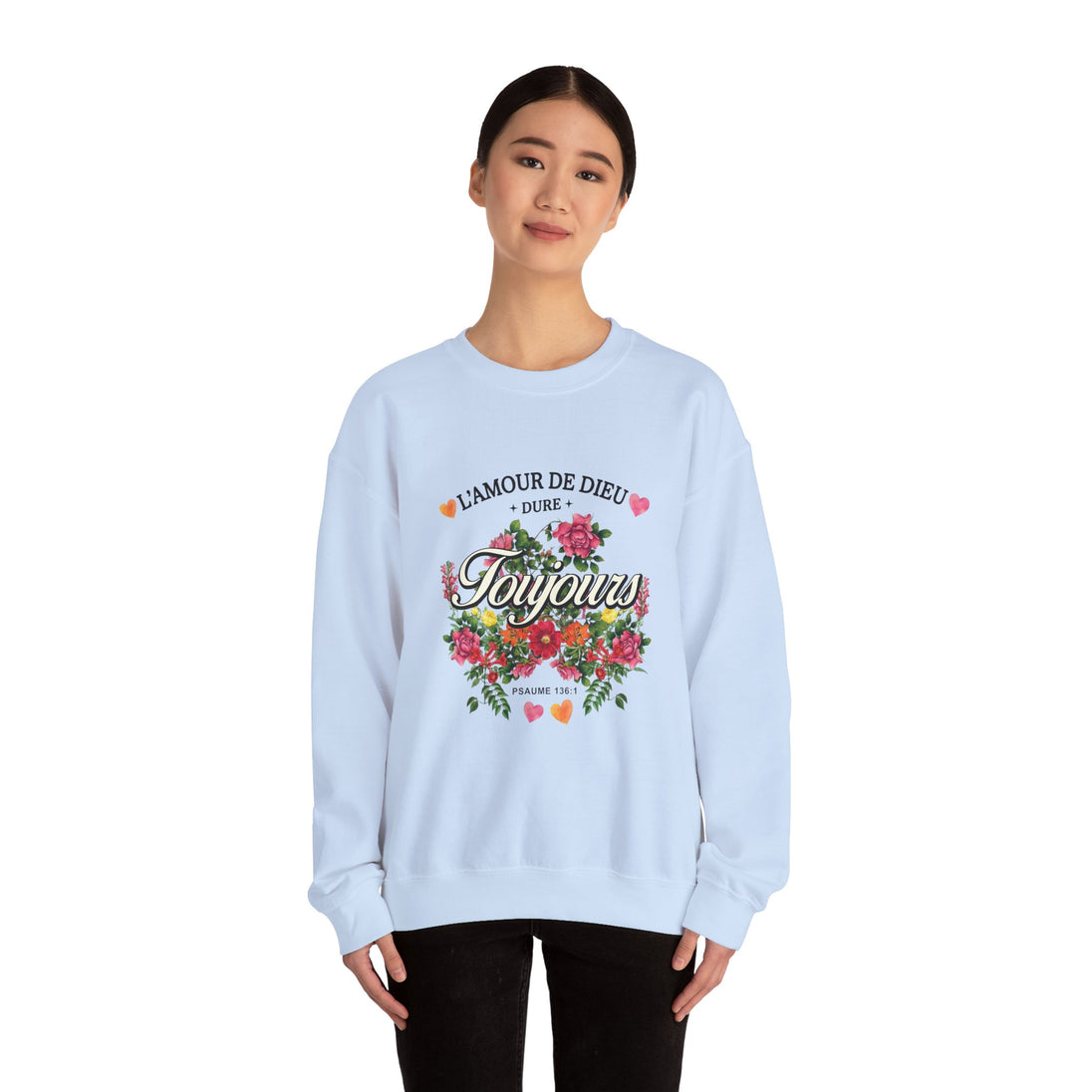 Une femme porte un sweatshirt blanc orné d'un motif floral et du texte L'amour de Dieu dure toujours.