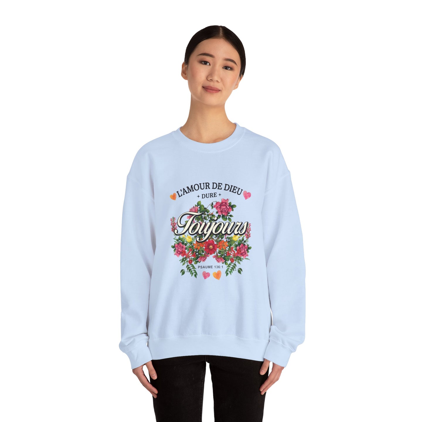 Une femme porte un sweatshirt blanc orné d'un motif floral et du texte L'amour de Dieu dure toujours.