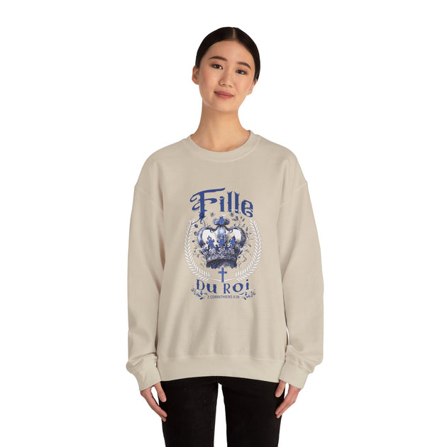 Une femme porte un sweat-shirt beige avec une couronne bleue et le texte Fille du Roi.