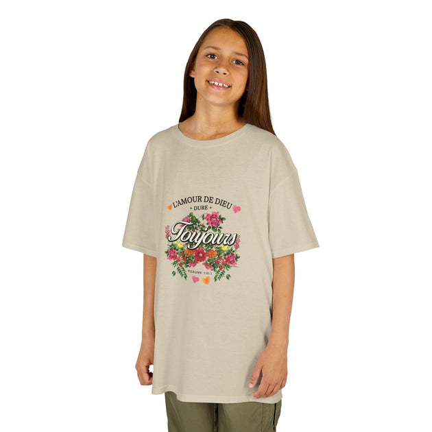 Une jeune fille porte un t-shirt beige en coton orné d'un motif floral et du texte L'Amour de Dieu.