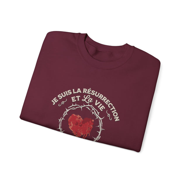 Sweat-shirt bordeaux plié avec un motif de cœur couronné d'épines et l'inscription Je suis la résurrection et la vie.