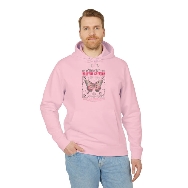 Un homme porte un sweat à capuche rose avec un motif de papillon et un texte religieux.