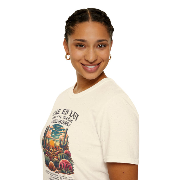 Une femme porte un t-shirt beige en coton orné d'une illustration de cactus et d'un texte religieux.