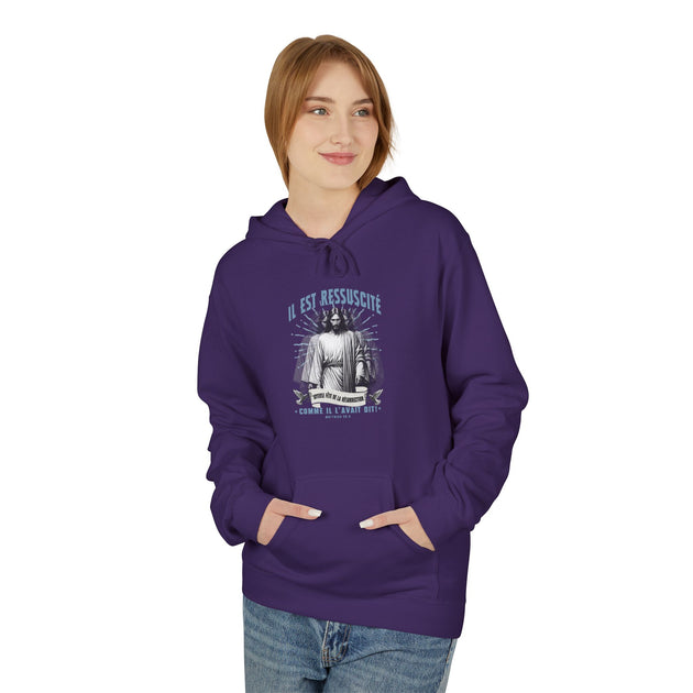 Une femme porte un sweat à capuche violet avec une illustration religieuse sur la poitrine.