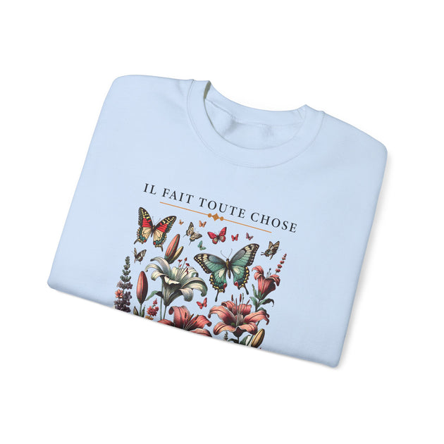 Sweatshirt bleu clair plié avec une illustration de fleurs et de papillons et le texte imprimé.