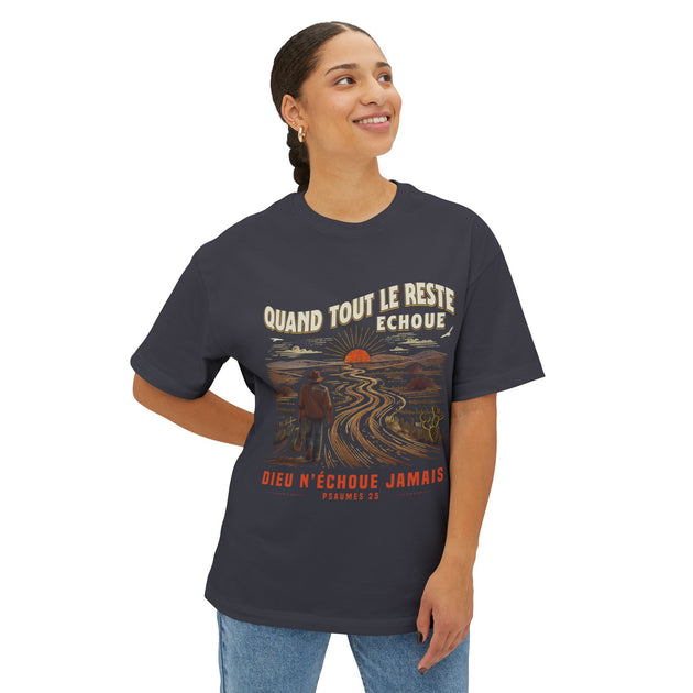 Une femme porte un t-shirt gris foncé avec une illustration de voyageur et un texte en français.