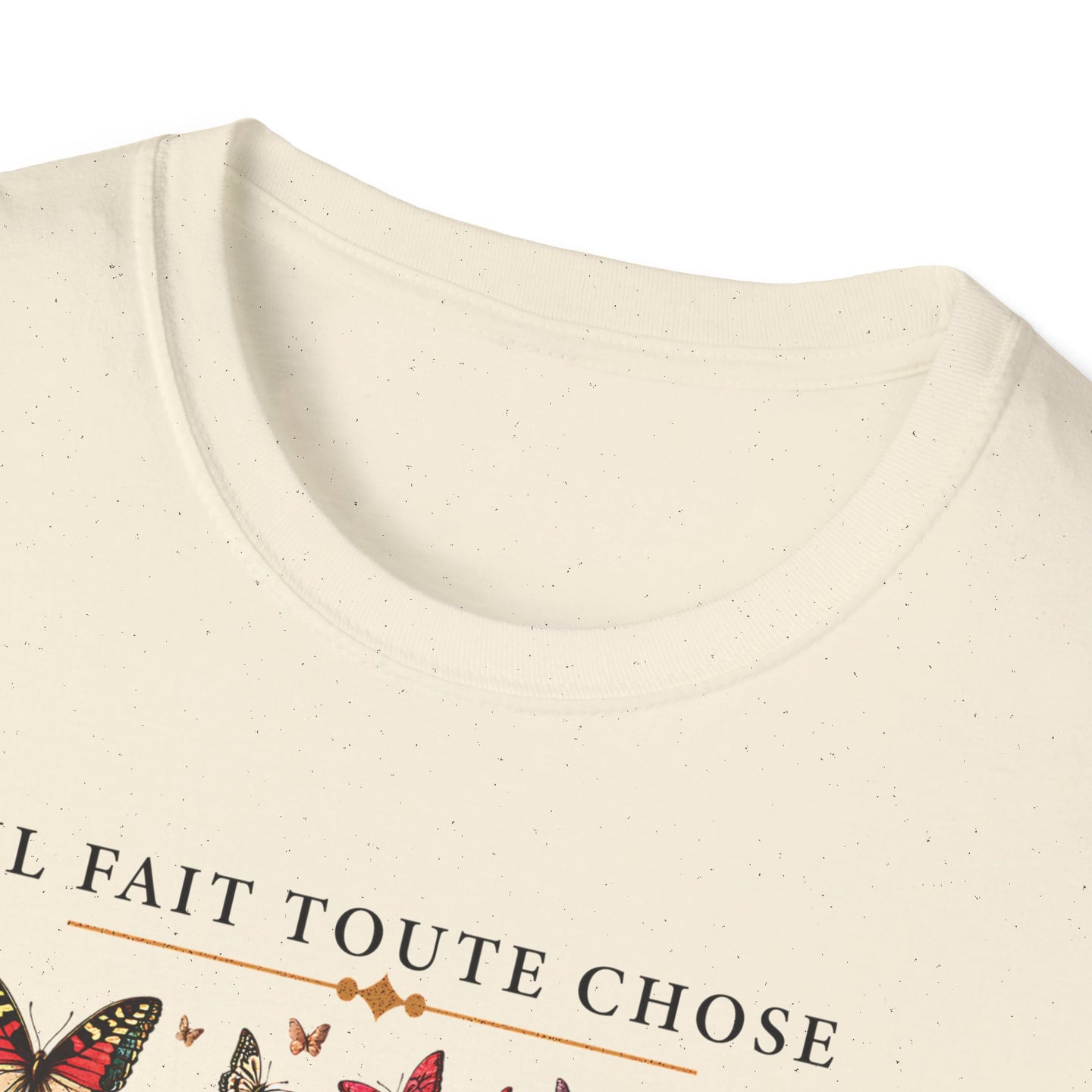 T-shirt beige chiné avec l'inscription Il fait toute chose et des motifs de papillons.