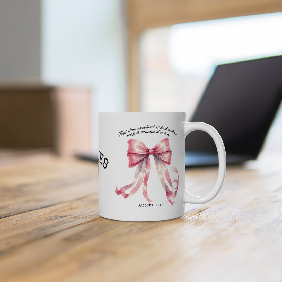 Un mug en céramique blanche orné d'un nœud rose et du verset biblique Jacques 1:17.