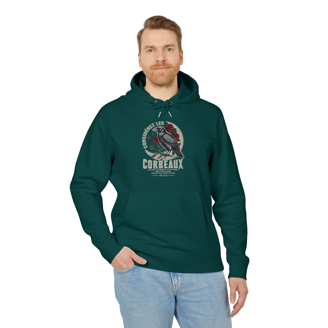 Un homme porte un sweat à capuche vert foncé avec une illustration de corbeau et des roses.