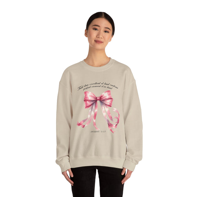 Une femme porte un sweatshirt beige orné d'un ruban rose aquarelle et du verset Jacques 1:17.