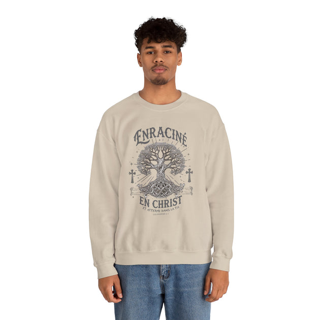 Un homme porte un sweatshirt beige avec une illustration d'arbre et le texte Enraciné en Christ.