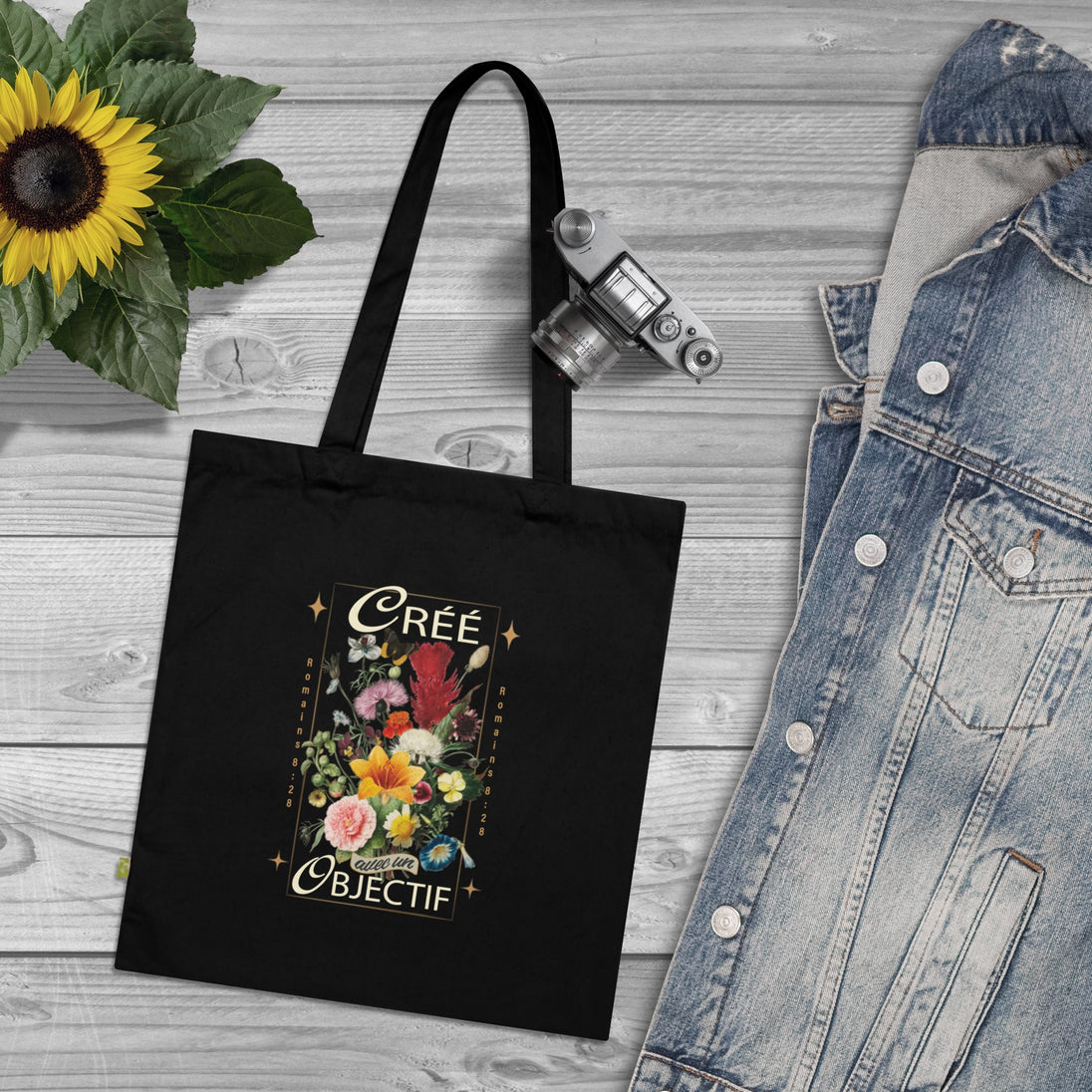 Tote bag noir en coton biologique orné d'un motif floral et de l'inscription Créé avec un objectif.