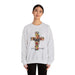 Une femme porte un sweat-shirt gris chiné orné d'une croix florale et de l'inscription Tout est accompli.